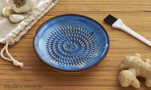 Keramische Kuechenreibe für Knoblauch, blau mit braunem Rand.